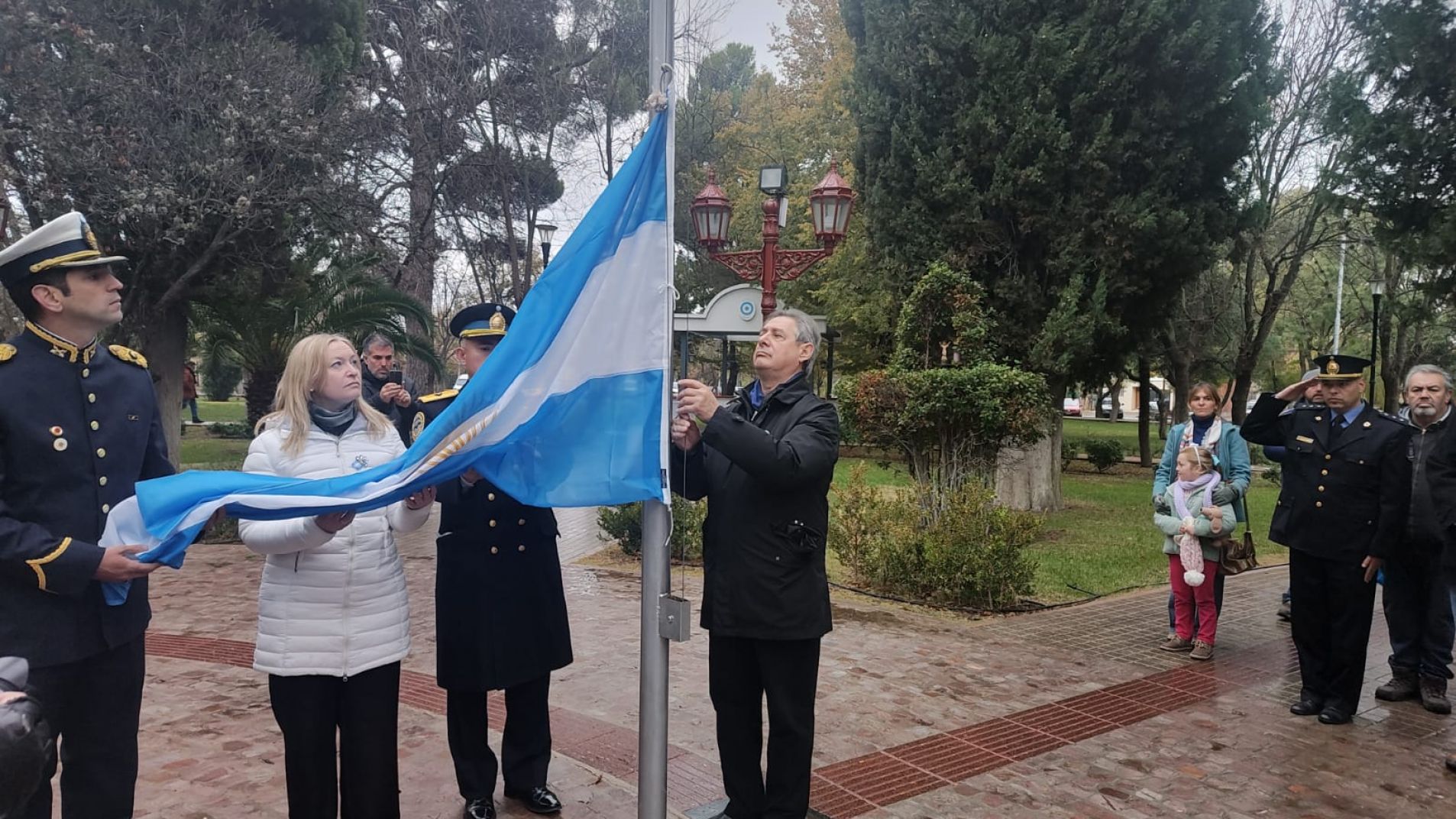 La vicegobernadora y el jefe comunal izaron la bandera en la plaza de la Villa 25 de Mayo.